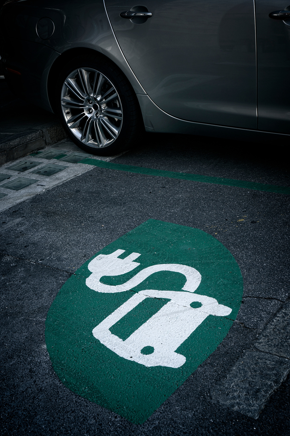 Green road sign painted on asphalt for electric vehicle charging stations